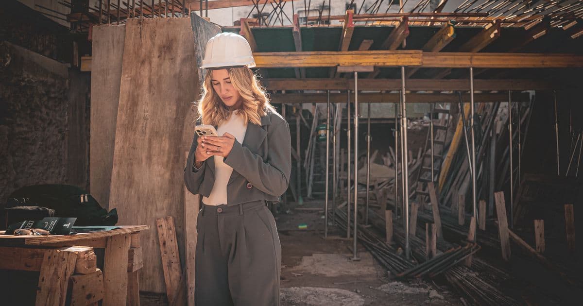 Profesional con casco consultando el móvil durante una intervención en obra