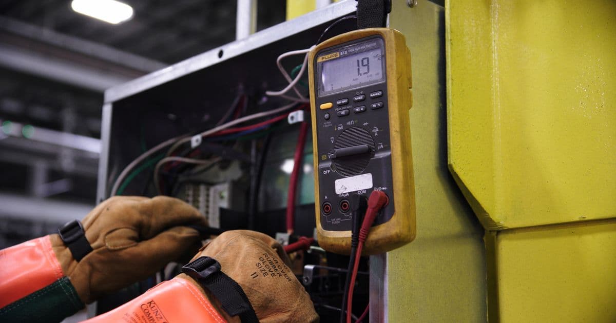 Técnico midiendo tensión con un multímetro en un cuadro eléctrico industrial