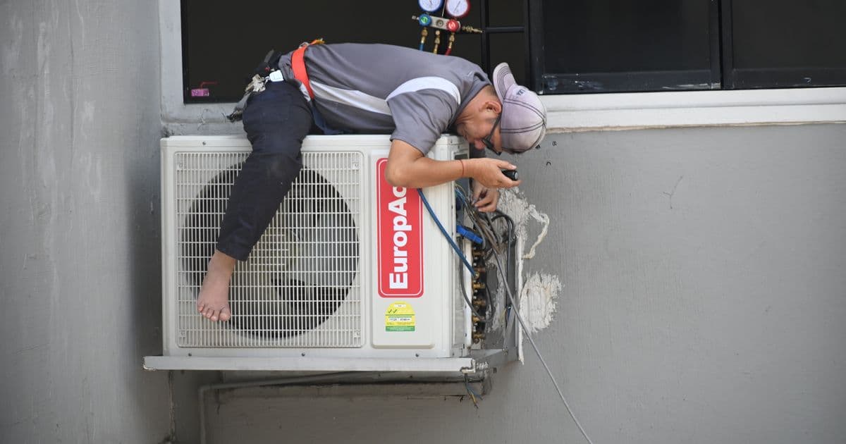 Técnico de servicio reparando un equipo de aire acondicionado en casa de un cliente